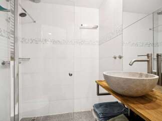 Step into a modern bathroom oasis! This stunning space features a sleek, frameless shower enclosure and elegant stone sink.