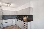 This modern kitchen boasts sleek cabinetry and a dark countertop, creating a stylish and functional space.