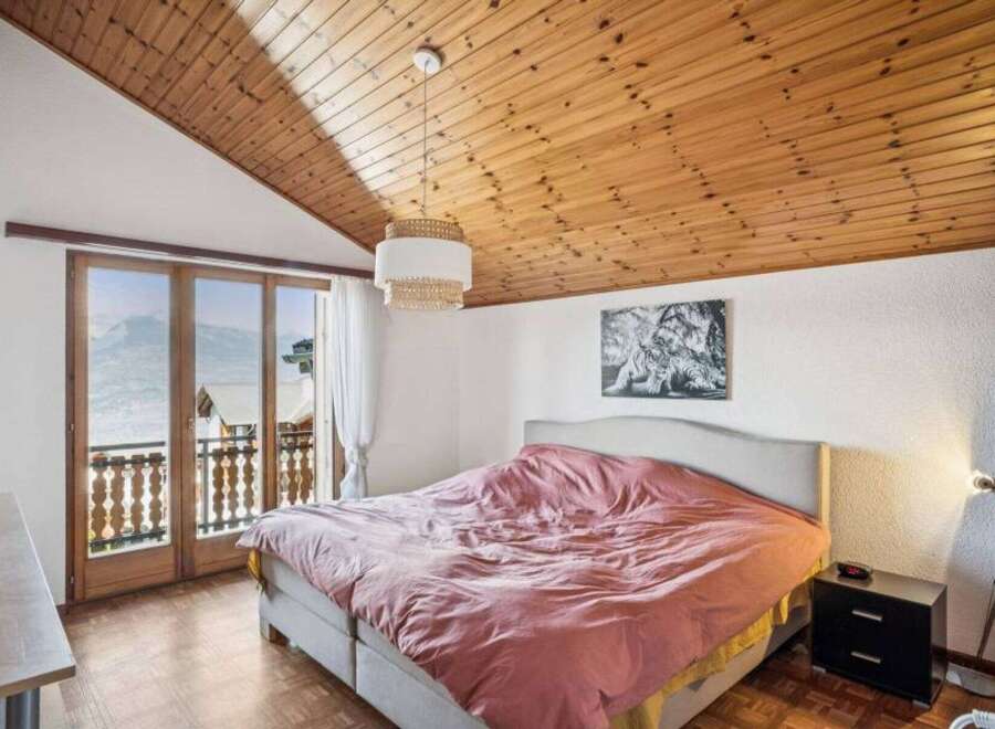 Experience the charm of this cozy bedroom featuring a stunning wooden ceiling and a comfortable bed.