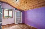 This charming room features a unique wooden ceiling and a vibrant purple accent wall, creating a cozy and inviting atmosphere.