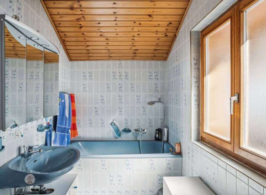 This charming bathroom features a unique wooden ceiling and light blue tiles, creating a cozy and inviting atmosphere.