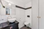 This modern bathroom features sleek white tiles and a stylish black vanity.