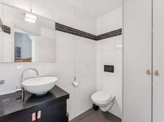 This modern bathroom features sleek white tiles and a stylish black vanity.