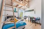 This charming bedroom features a unique loft bed design with a wooden ladder, maximizing space and adding a playful touch.