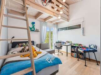 This charming bedroom features a unique loft bed design with a wooden ladder, maximizing space and adding a playful touch.