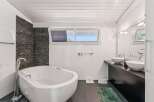This modern bathroom features a sleek, white bathtub and a stylish stone accent wall, creating a spa-like atmosphere.