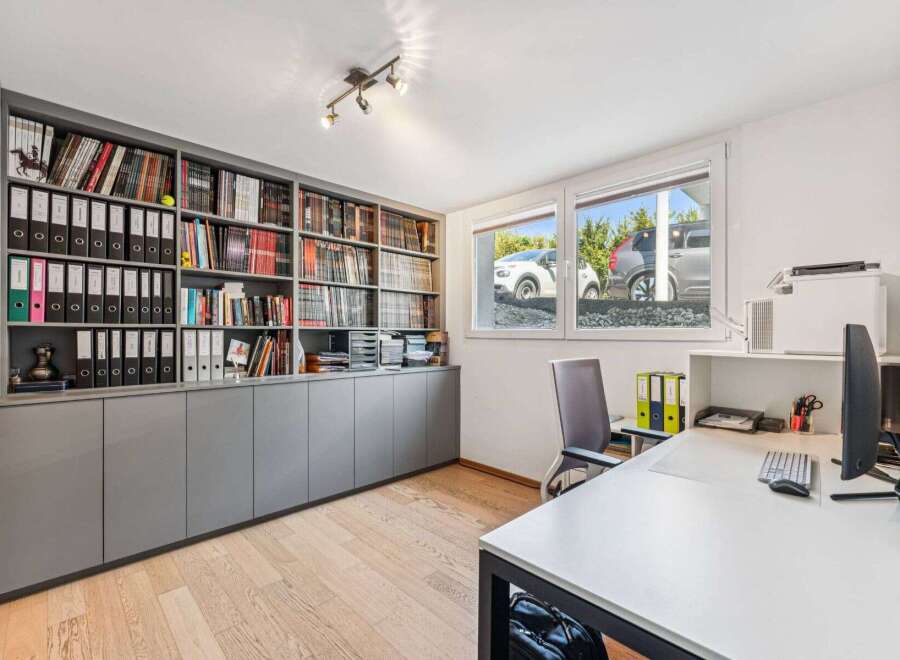 This well-lit home office features a built-in bookshelf, perfect for organizing books and documents.