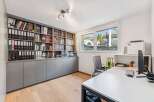 This well-lit home office features a built-in bookshelf, perfect for organizing books and documents.