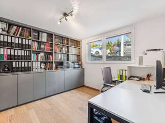 This well-lit home office features a built-in bookshelf, perfect for organizing books and documents.