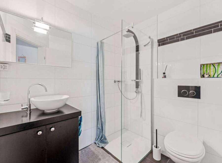 This modern bathroom features a sleek design with clean lines and bright white tiles.