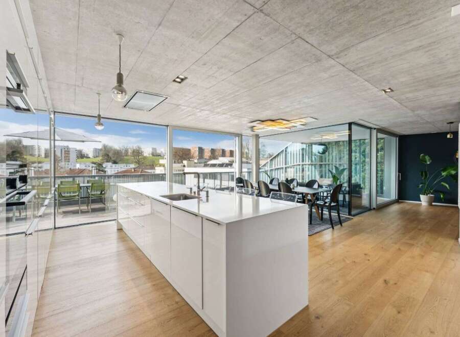 Experience modern luxury in this stunning property, featuring an open-plan kitchen with a sleek island and expansive windows.