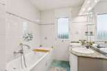 Step into this bright and inviting bathroom, featuring a pristine white bathtub and a stylish double vanity with a granite countertop.