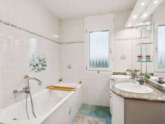 Step into this bright and inviting bathroom, featuring a pristine white bathtub and a stylish double vanity with a granite countertop.