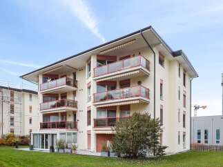 Discover modern living in this stunning apartment building, featuring spacious balconies with glass railings and awnings.