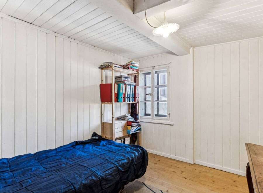 Discover the charm of this cozy bedroom, featuring a unique wooden shelf filled with books and files.