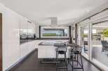 This modern kitchen boasts sleek, white cabinetry and a spacious island, perfect for culinary enthusiasts.