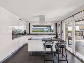This modern kitchen boasts sleek, white cabinetry and a spacious island, perfect for culinary enthusiasts.