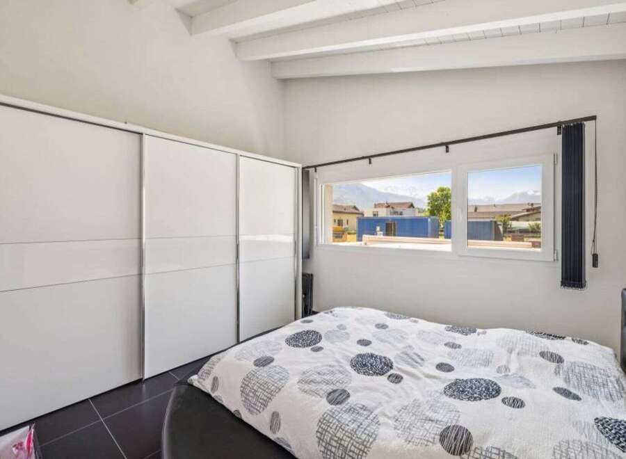This bright and airy bedroom features a large, modern closet and a comfortable bed with a stylish patterned duvet.