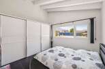 This bright and airy bedroom features a large, modern closet and a comfortable bed with a stylish patterned duvet.