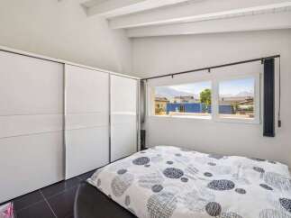 This bright and airy bedroom features a large, modern closet and a comfortable bed with a stylish patterned duvet.