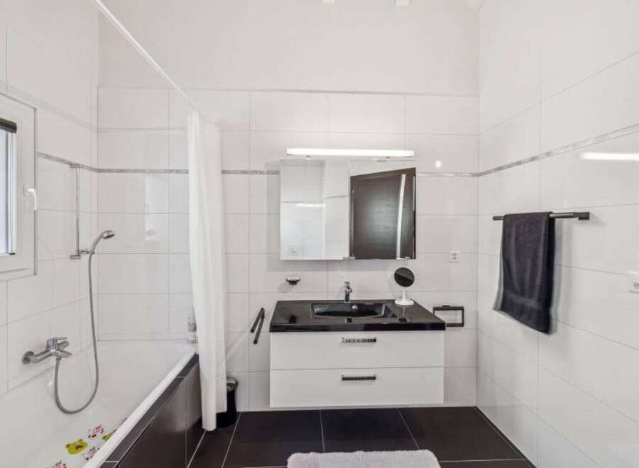 This modern bathroom features a sleek design with a black countertop and white cabinetry.