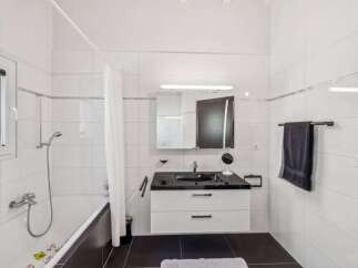 This modern bathroom features a sleek design with a black countertop and white cabinetry.