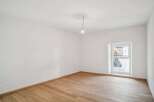 This bright and airy room features pristine white walls and beautiful hardwood floors, creating a clean and inviting atmosphere.