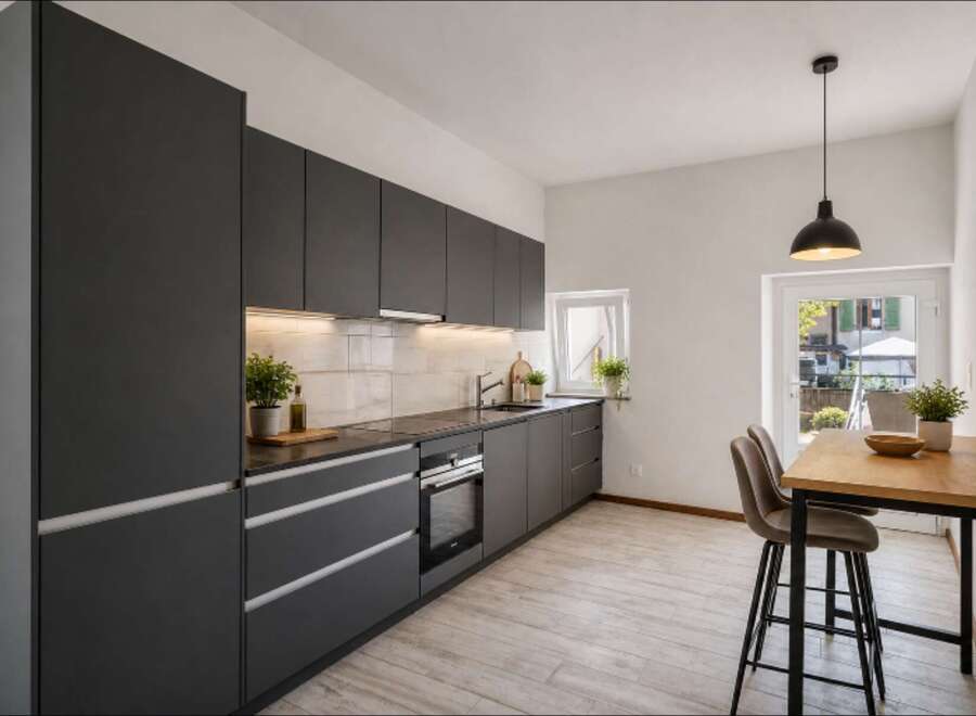 This modern kitchen boasts sleek, dark gray cabinetry and a minimalist design, perfect for contemporary living.