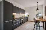 This modern kitchen boasts sleek, dark gray cabinetry and a minimalist design, perfect for contemporary living.