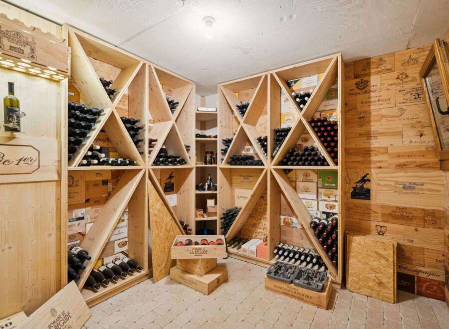 This stunning wine cellar showcases a sophisticated design with custom wooden shelving, perfect for storing and displaying a vast collection of fine wines.