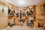 This stunning wine cellar showcases a sophisticated design with custom wooden shelving, perfect for storing and displaying a vast collection of fine wines.