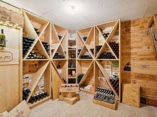 This stunning wine cellar showcases a sophisticated design with custom wooden shelving, perfect for storing and displaying a vast collection of fine wines.