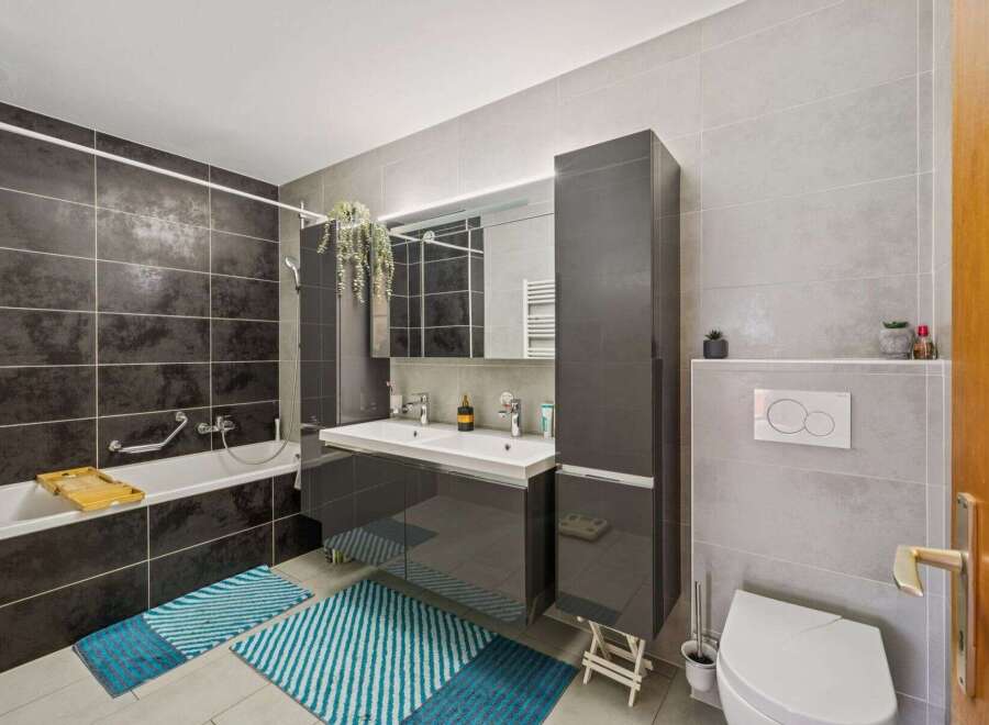Step into a modern bathroom oasis! This stunning space features sleek gray tiles, a double vanity, and ample storage.