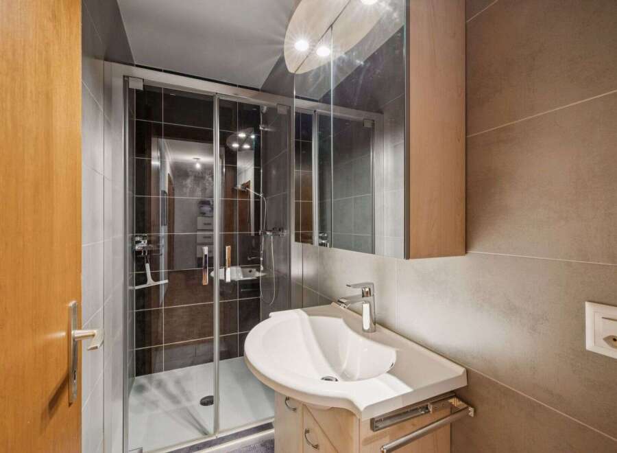 Step into this modern bathroom, featuring a sleek shower enclosure and a stylish vanity.