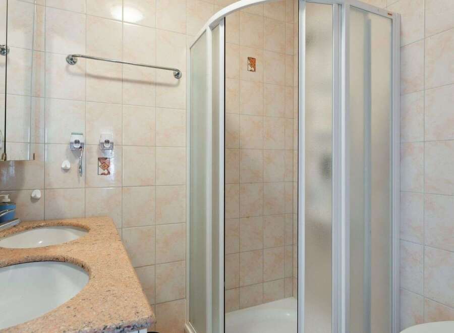 This bathroom features a modern shower with a glass door, offering a sleek and contemporary design.