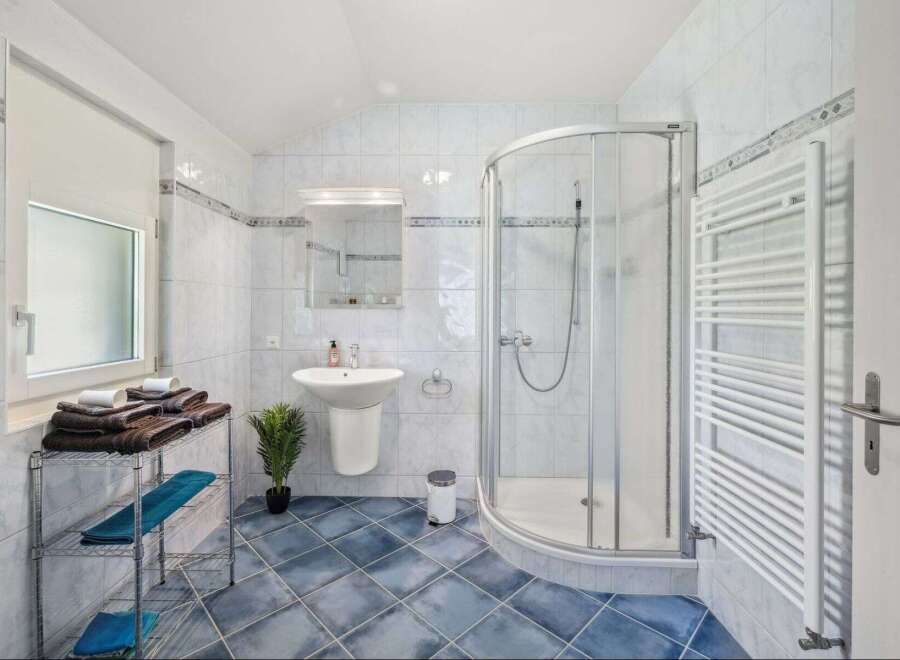Step into this bright and airy bathroom, featuring a modern shower and a sleek pedestal sink.