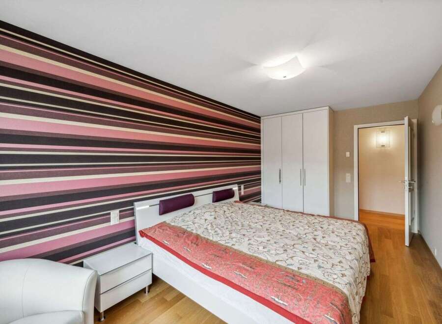 This stylish bedroom features a striking striped accent wall, creating a bold and modern aesthetic.