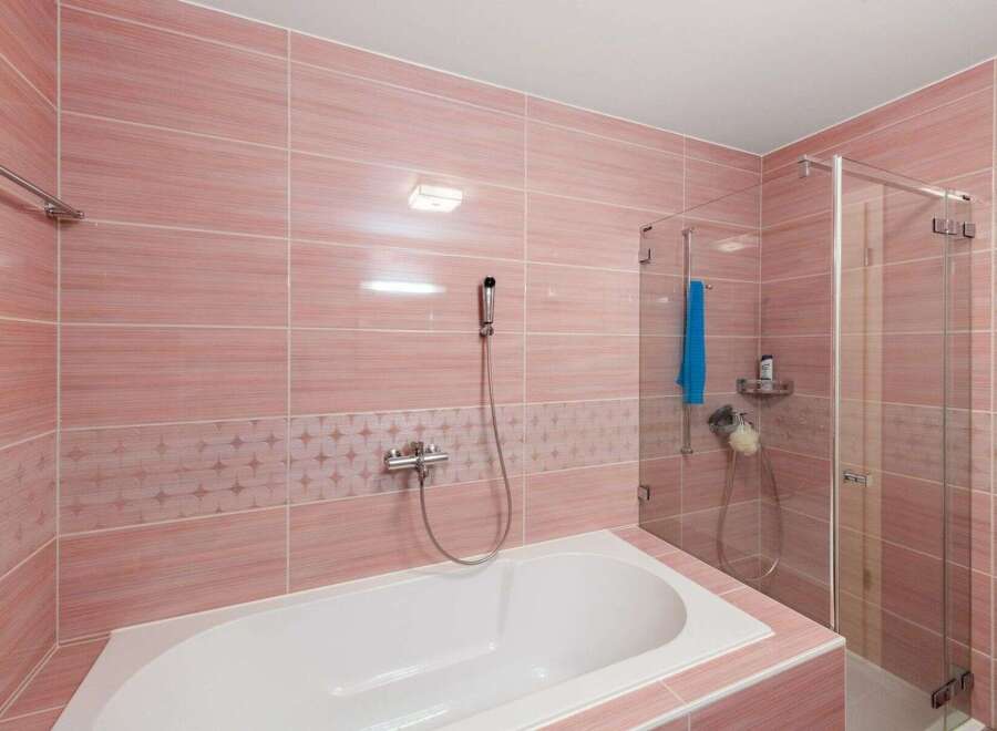 Step into this beautifully designed bathroom, featuring elegant pink tiles that create a serene and inviting atmosphere.