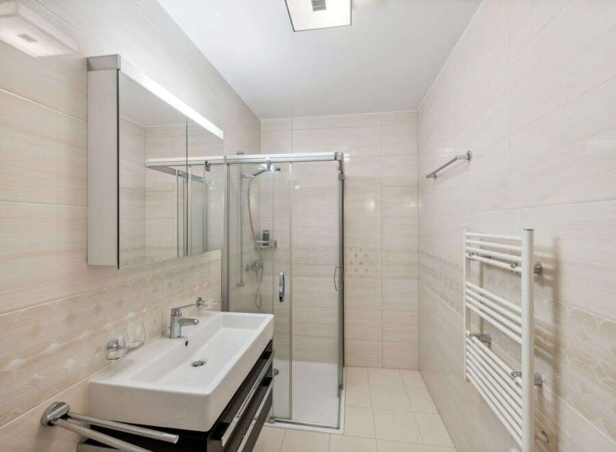 Step into this modern bathroom, featuring a sleek glass shower enclosure and a stylish vanity.