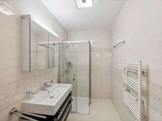 Step into this modern bathroom, featuring a sleek glass shower enclosure and a stylish vanity.