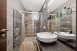 This modern bathroom features a sleek design with gray tiled walls and a glass shower enclosure.