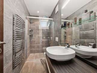 This modern bathroom features a sleek design with gray tiled walls and a glass shower enclosure.