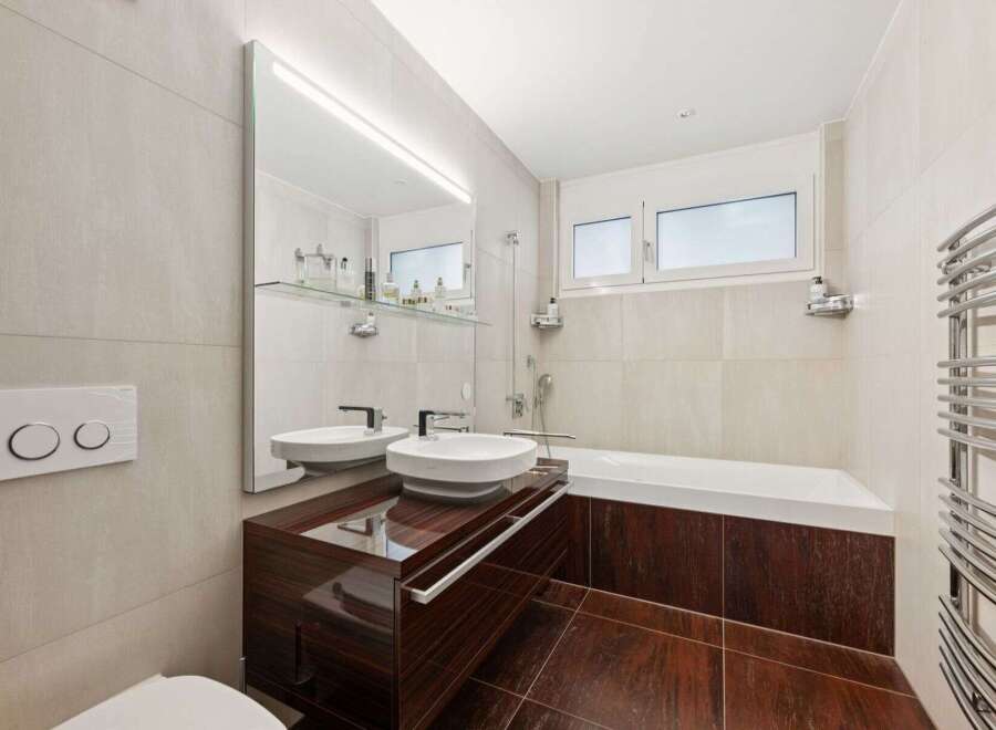 This modern bathroom features a sleek design with a dark wood vanity and matching flooring.