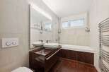 This modern bathroom features a sleek design with a dark wood vanity and matching flooring.