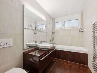 This modern bathroom features a sleek design with a dark wood vanity and matching flooring.