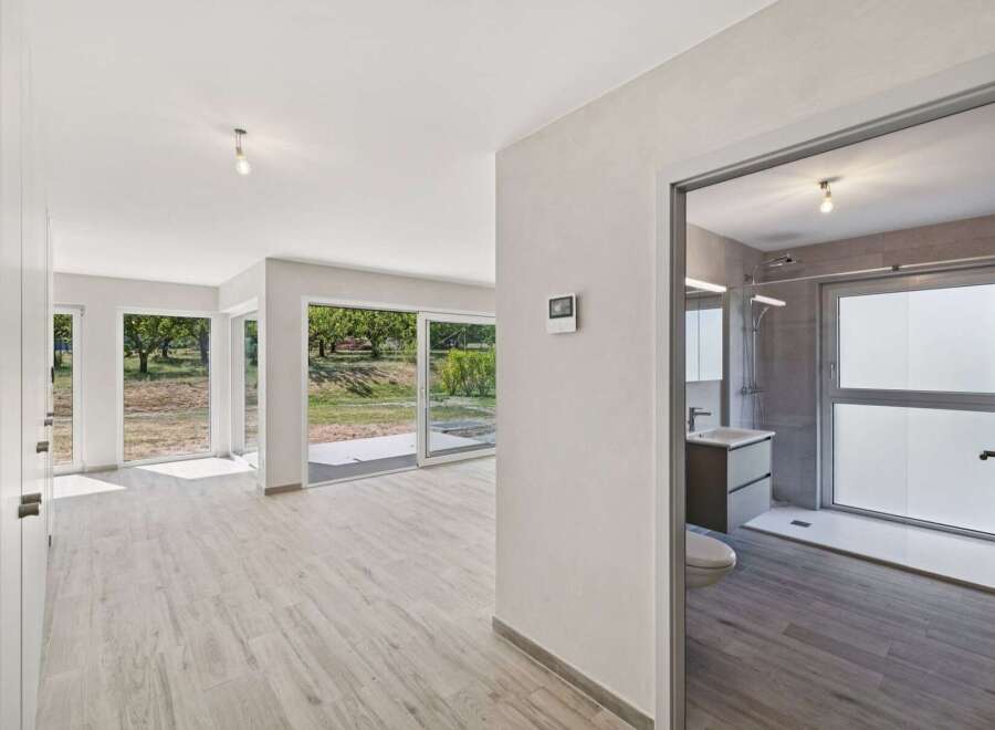 Experience modern living in this spacious home featuring expansive windows that flood the interior with natural light and offer picturesque views of the surrounding greenery.