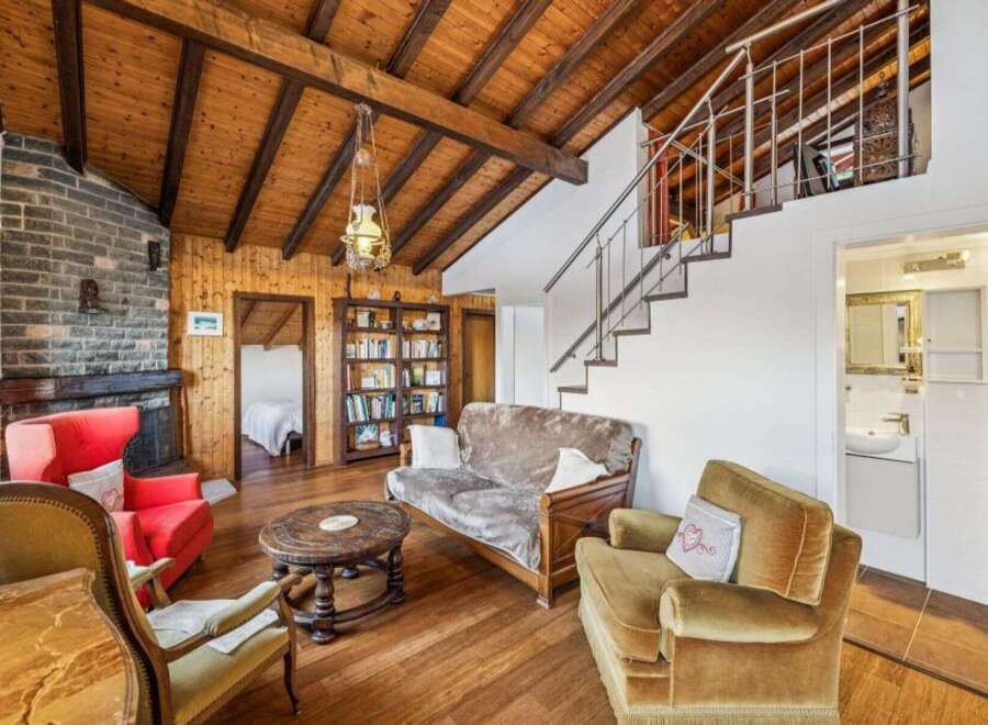 This charming property boasts a cozy living space with a rustic wooden ceiling and a brick fireplace, creating a warm and inviting atmosphere.