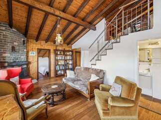 This charming property boasts a cozy living space with a rustic wooden ceiling and a brick fireplace, creating a warm and inviting atmosphere.