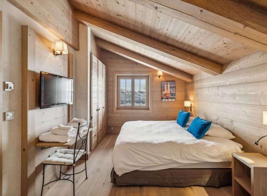 Experience the charm of this cozy bedroom featuring a rustic wooden interior and a comfortable bed.