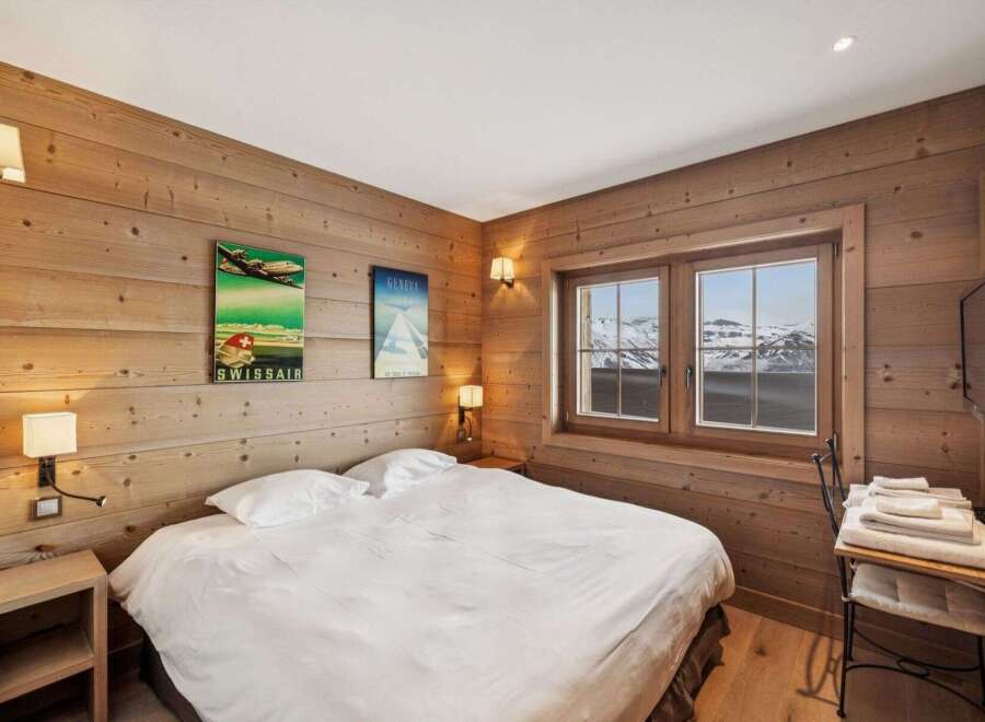 Experience the cozy charm of this bedroom, featuring warm wooden walls and a comfortable bed.